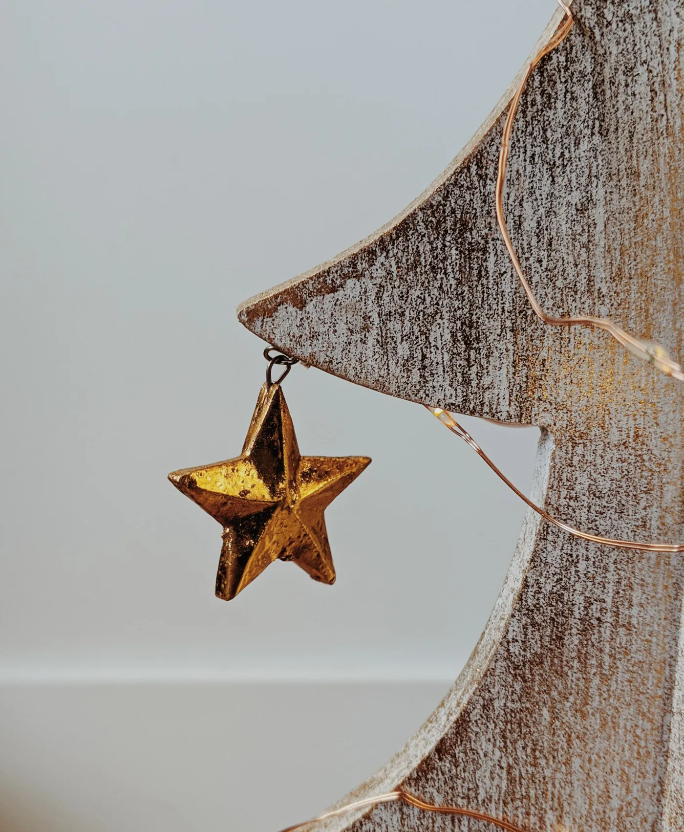 A close-up of a minimalist wooden Christmas tree adorned with a golden star ornament, perfect for holiday decor inspiration.