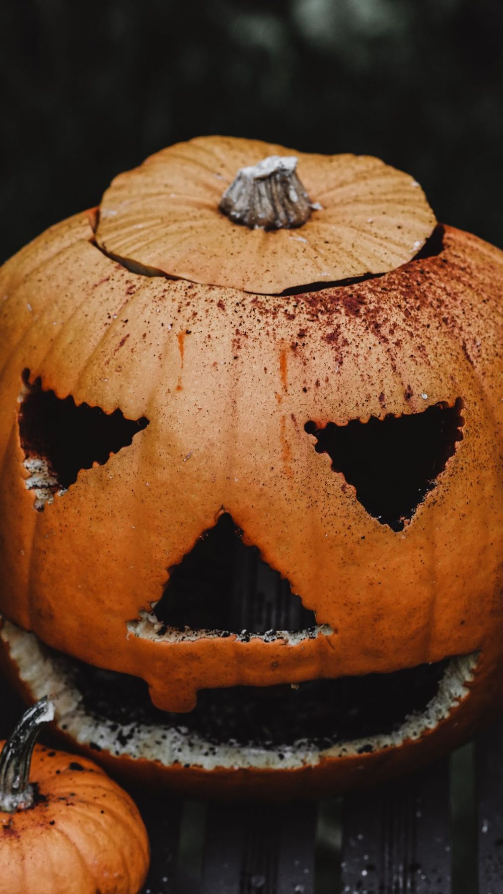 A close-up of a spooky carved jack-o'-lantern with triangular eyes and a grinning mouth, perfect for Halloween.