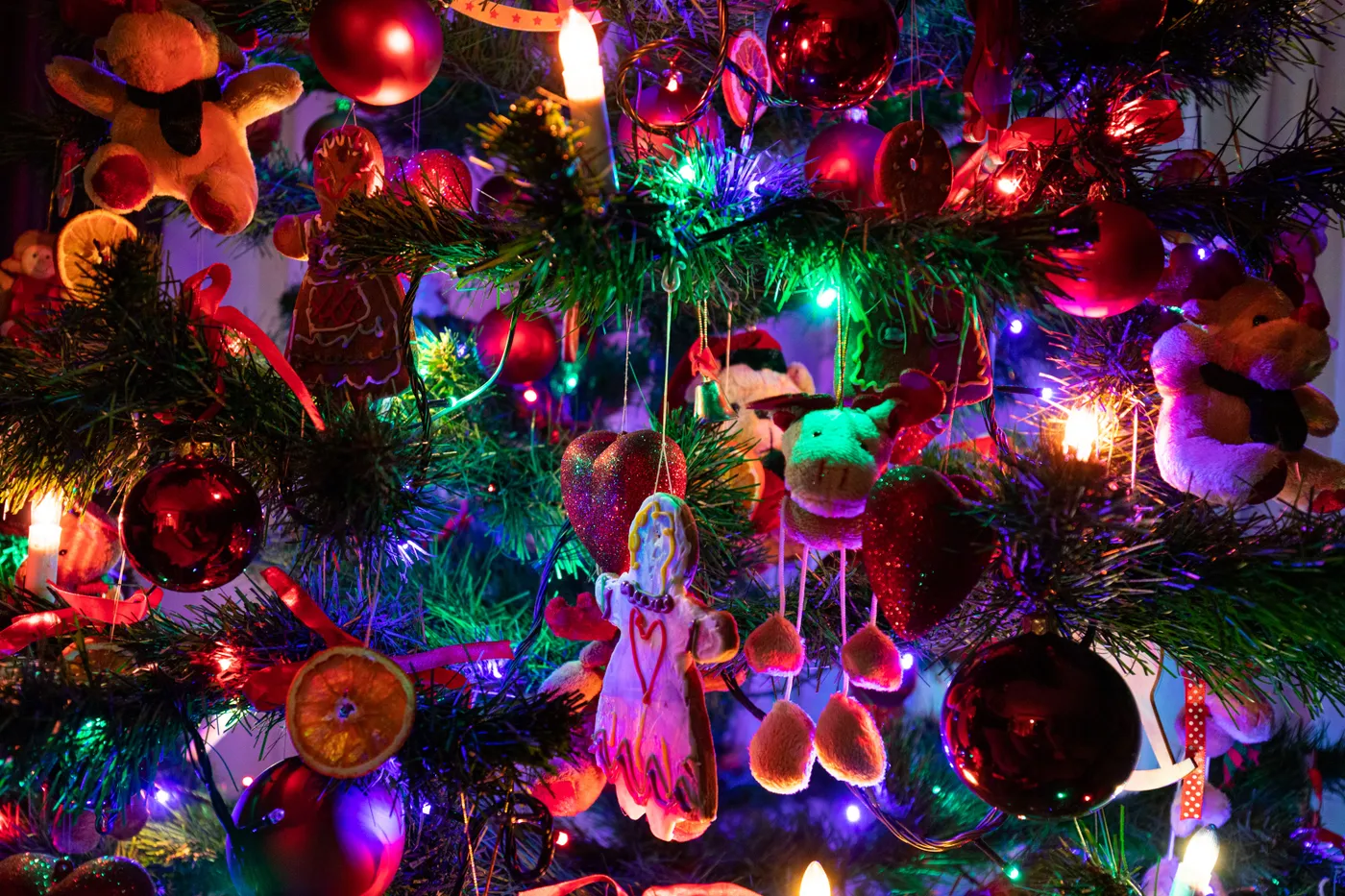 A colorful and festive close-up of a Christmas tree adorned with lights and ornaments.