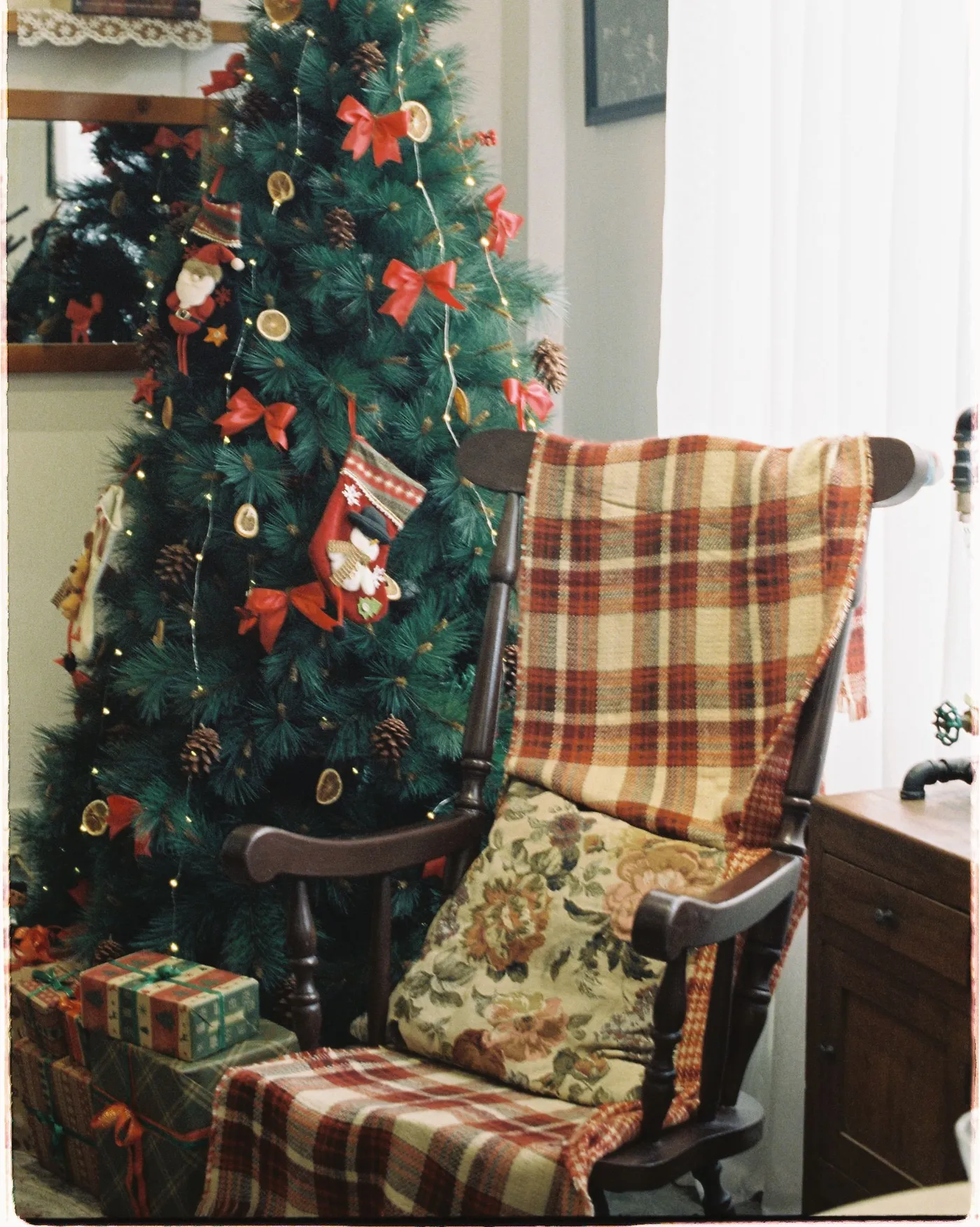 A comfortable armchair beside a beautifully decorated Christmas tree with gifts.