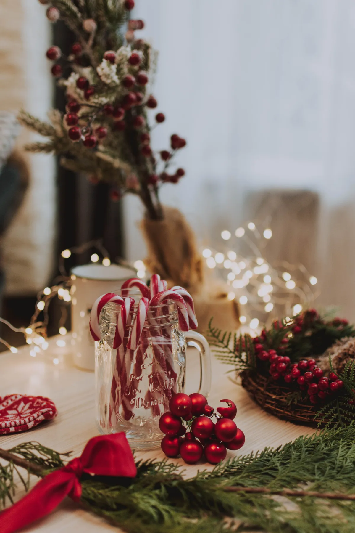 A festive arrangement of candy canes, red berries, and greenery in a cozy holiday setting.