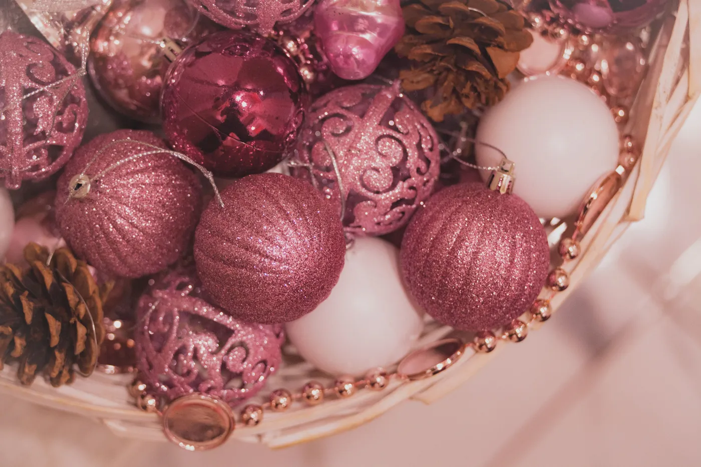 A festive arrangement of pink and white Christmas ornaments with pinecones, perfect for holiday decor.