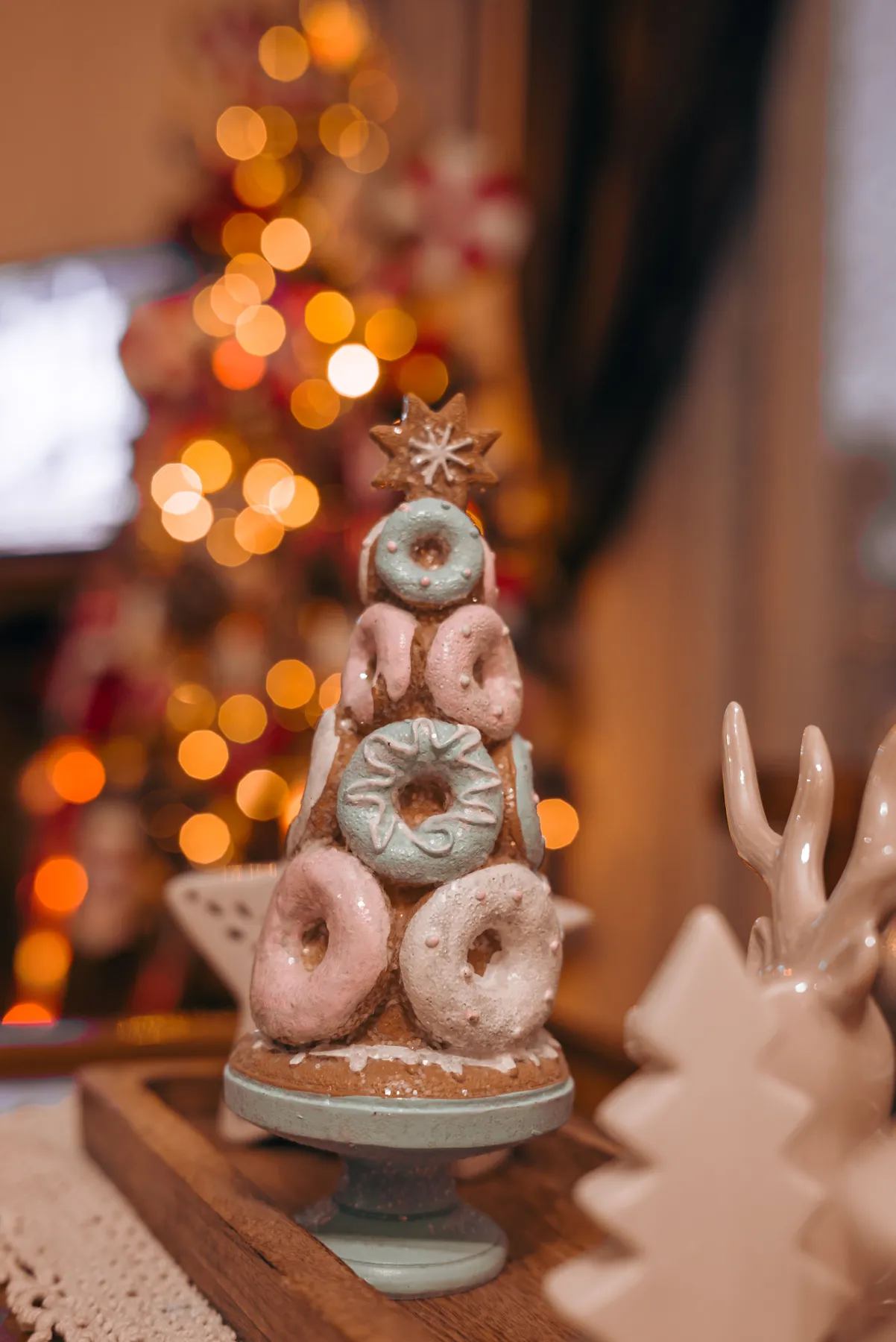 A festive doughnut tower with bokeh lights and a Christmas tree in the background.
