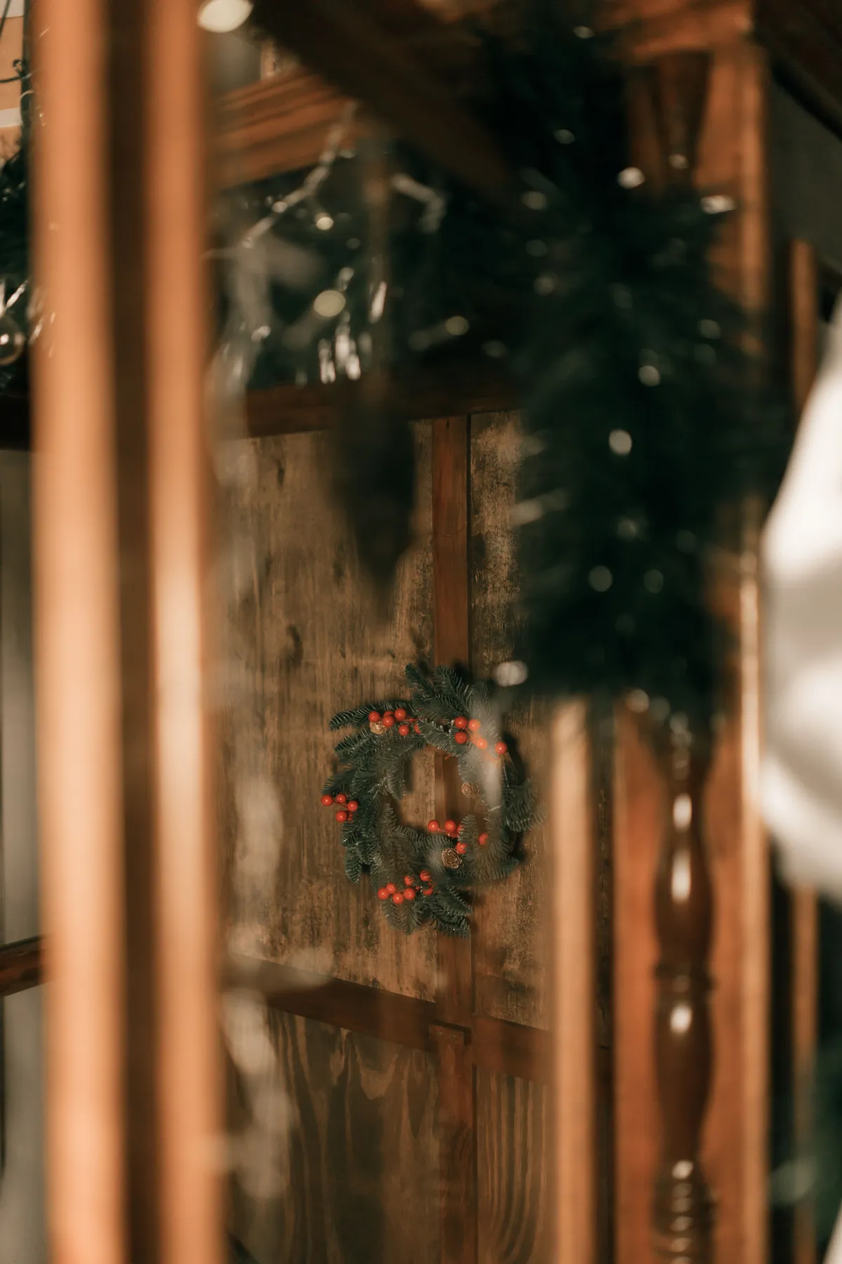 A festive holiday wreath with red berries hangs on a rustic wooden door, creating a cozy atmosphere.