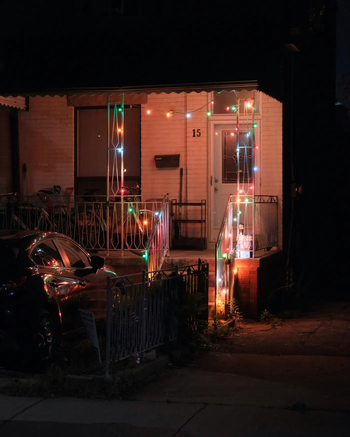 A house porch decorated with colorful string lights at night