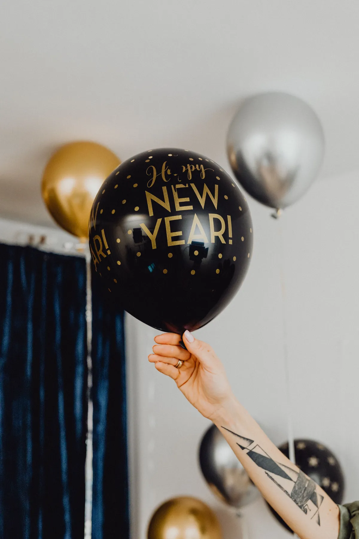 A joyful hand holding a New Year balloon against a festive background.