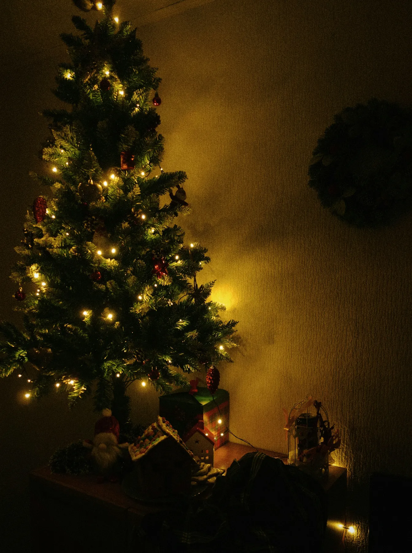 a lit christmas tree in the corner of a room