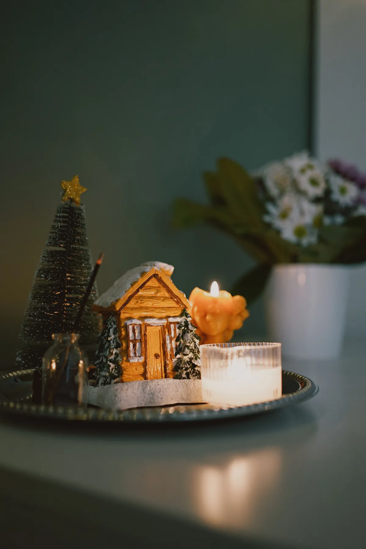 A mini winter cabin scene with candles and tree for festive decor.