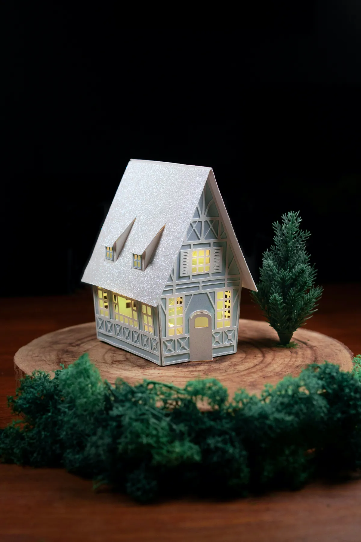 a paper model of a house sitting on top of a tree stump