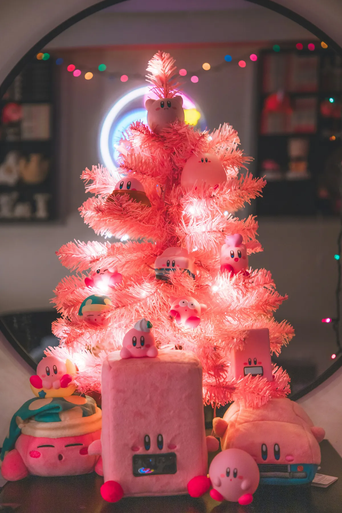 A pink christmas tree with a bunch of small toys around it