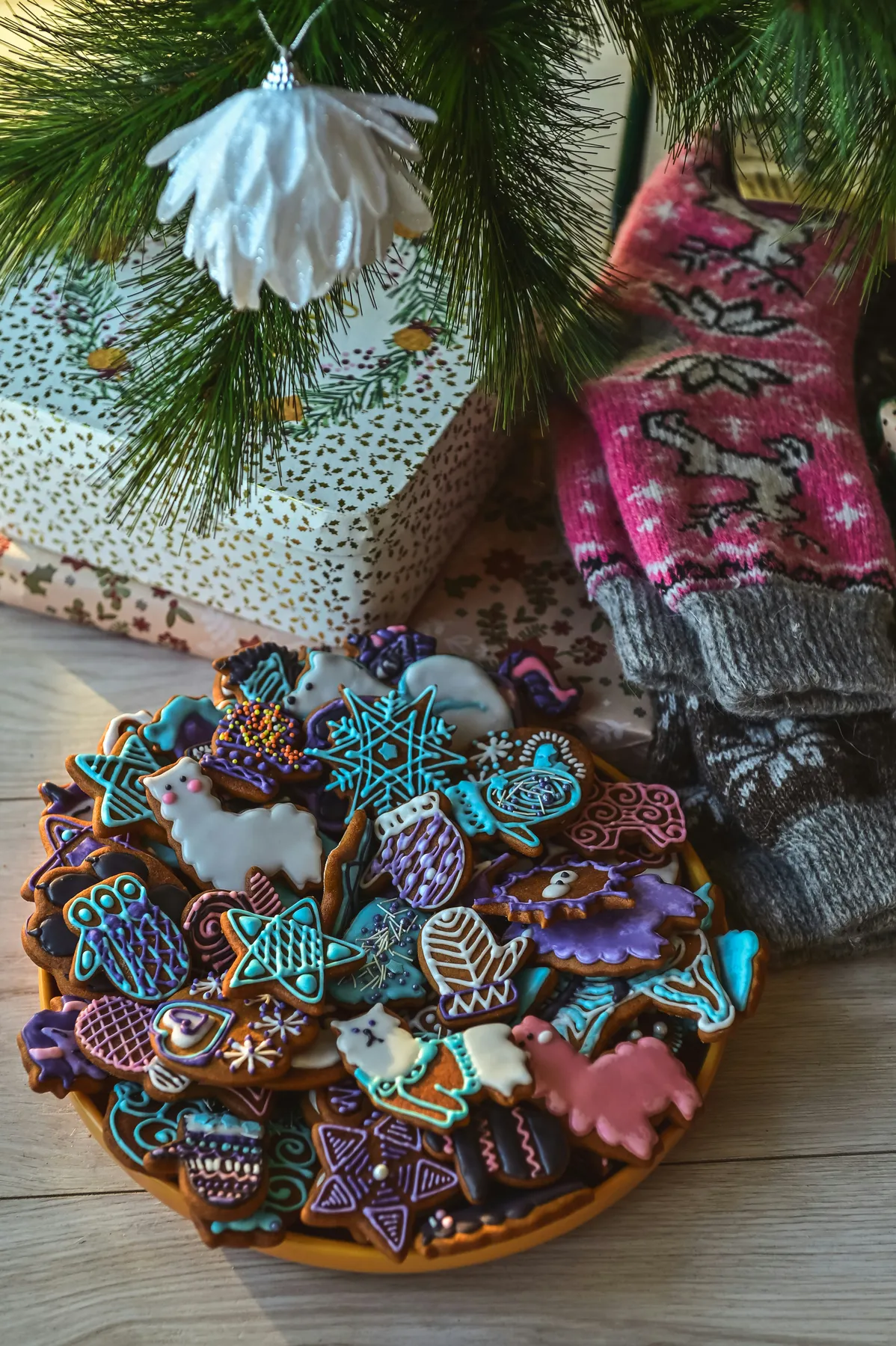 A plate of decorated cookies next to a christmas tree