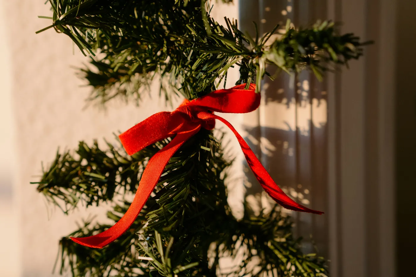 A red ribbon tied around a green garland