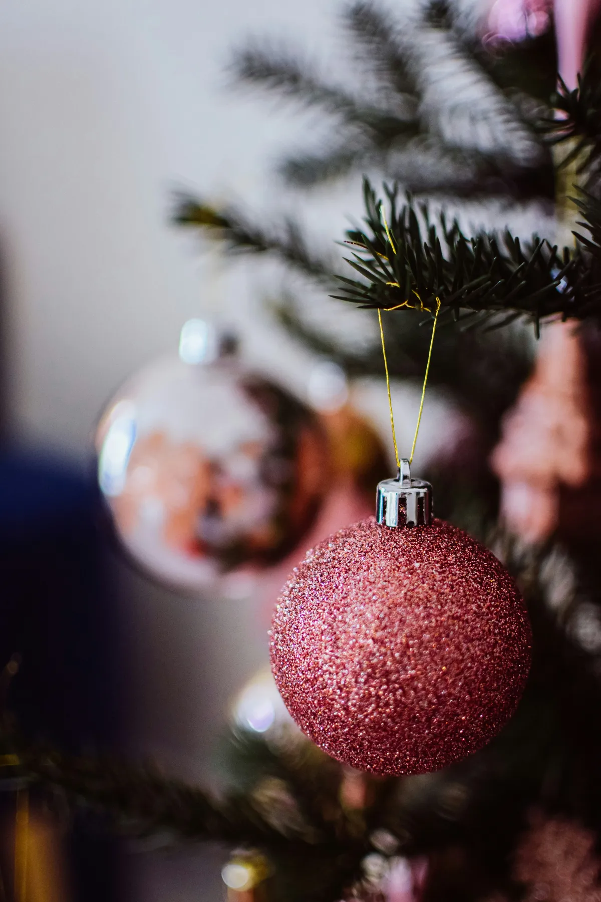 A sparkly pink ornament hangs on a christmas tree