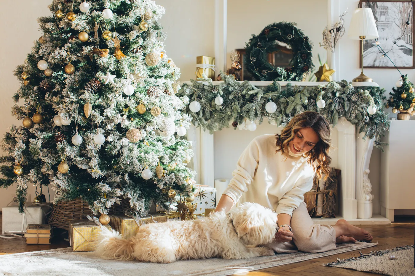 A woman sitting with her dog by a decorated Christmas tree, enjoying the cozy holiday ambiance at home.