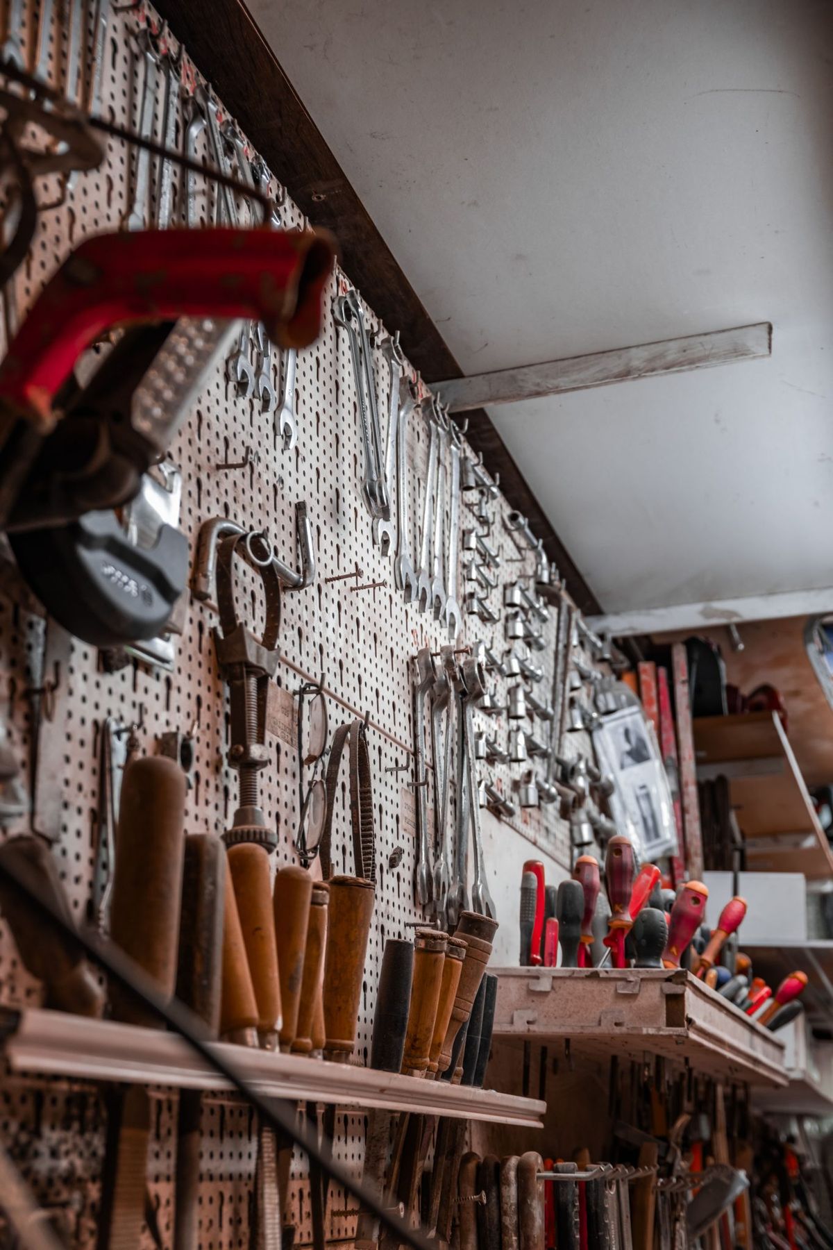 A workshop wall filled with various tools hanging for easy access and organization.