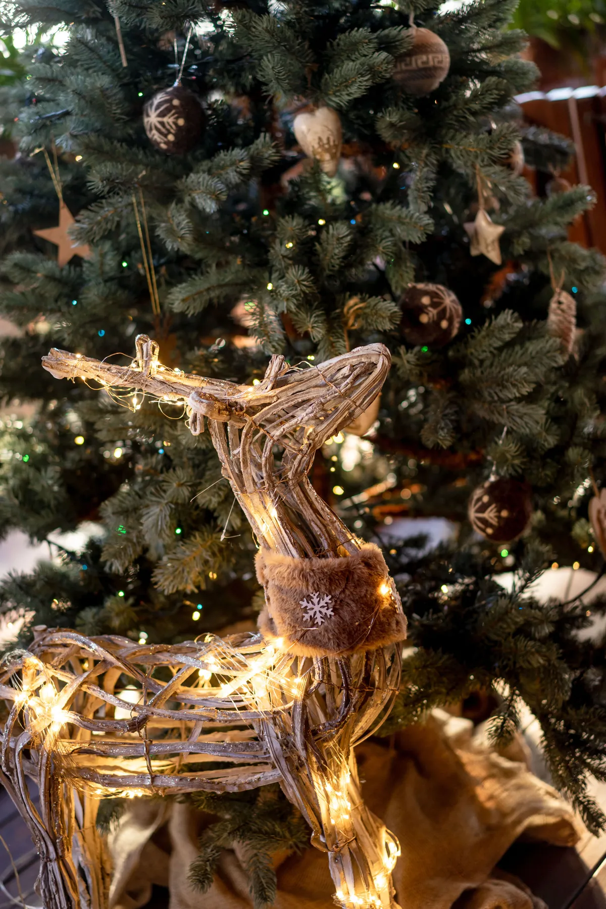 Beautifully decorated Christmas tree with a glowing deer ornament in warm lighting.