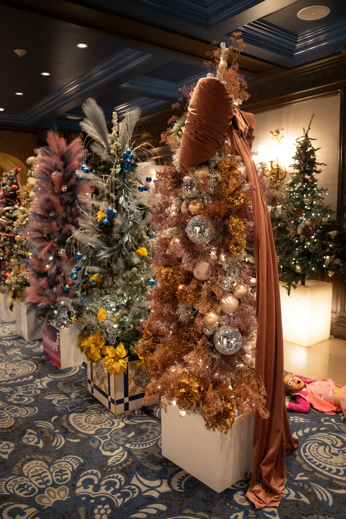 Beautifully decorated Christmas trees with unique ornaments in a festive indoor setting.