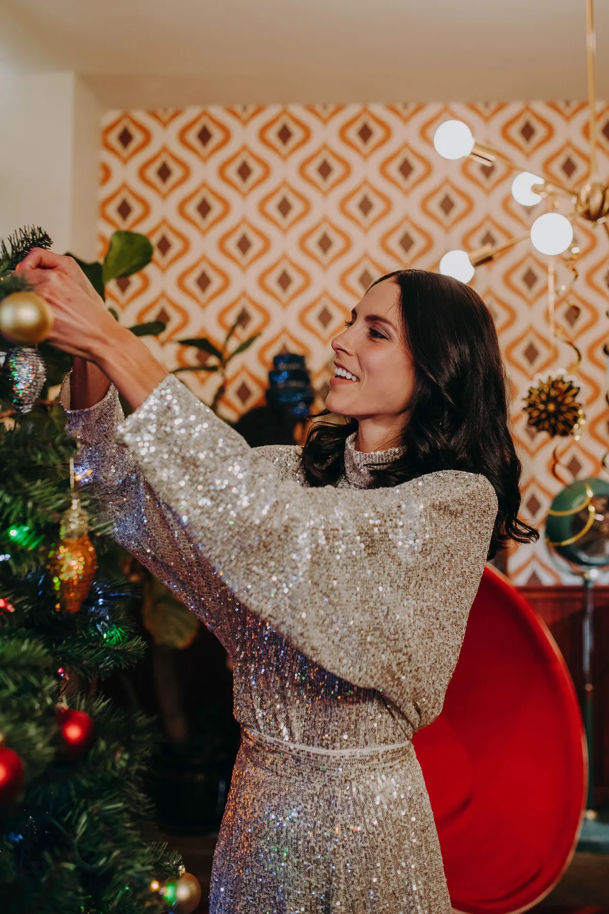 Caucasian woman decorates a Christmas tree with ornaments in a stylishly decorated living room.