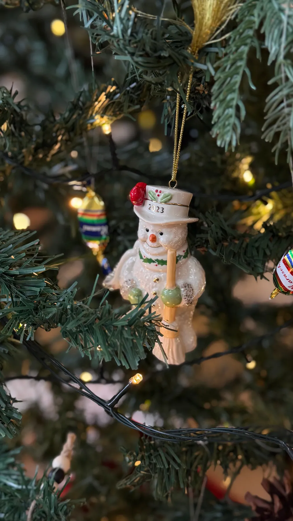 Charming snowman ornament with lights on a Christmas tree. Perfect holiday decor.