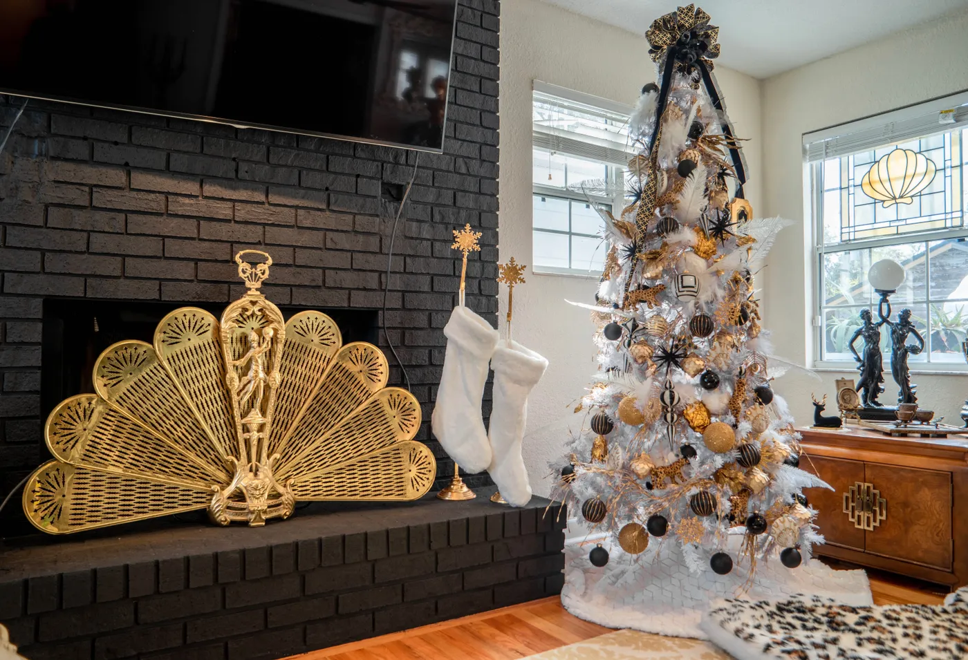 Chic living room corner with a white Christmas tree, golden accents, and stockings.
