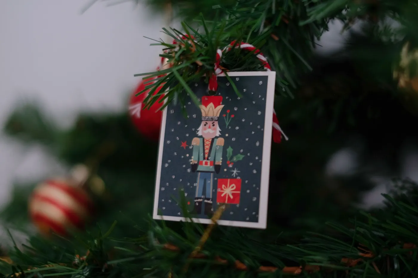 Close-up of a Christmas nutcracker ornament hanging on a decorated tree branch.