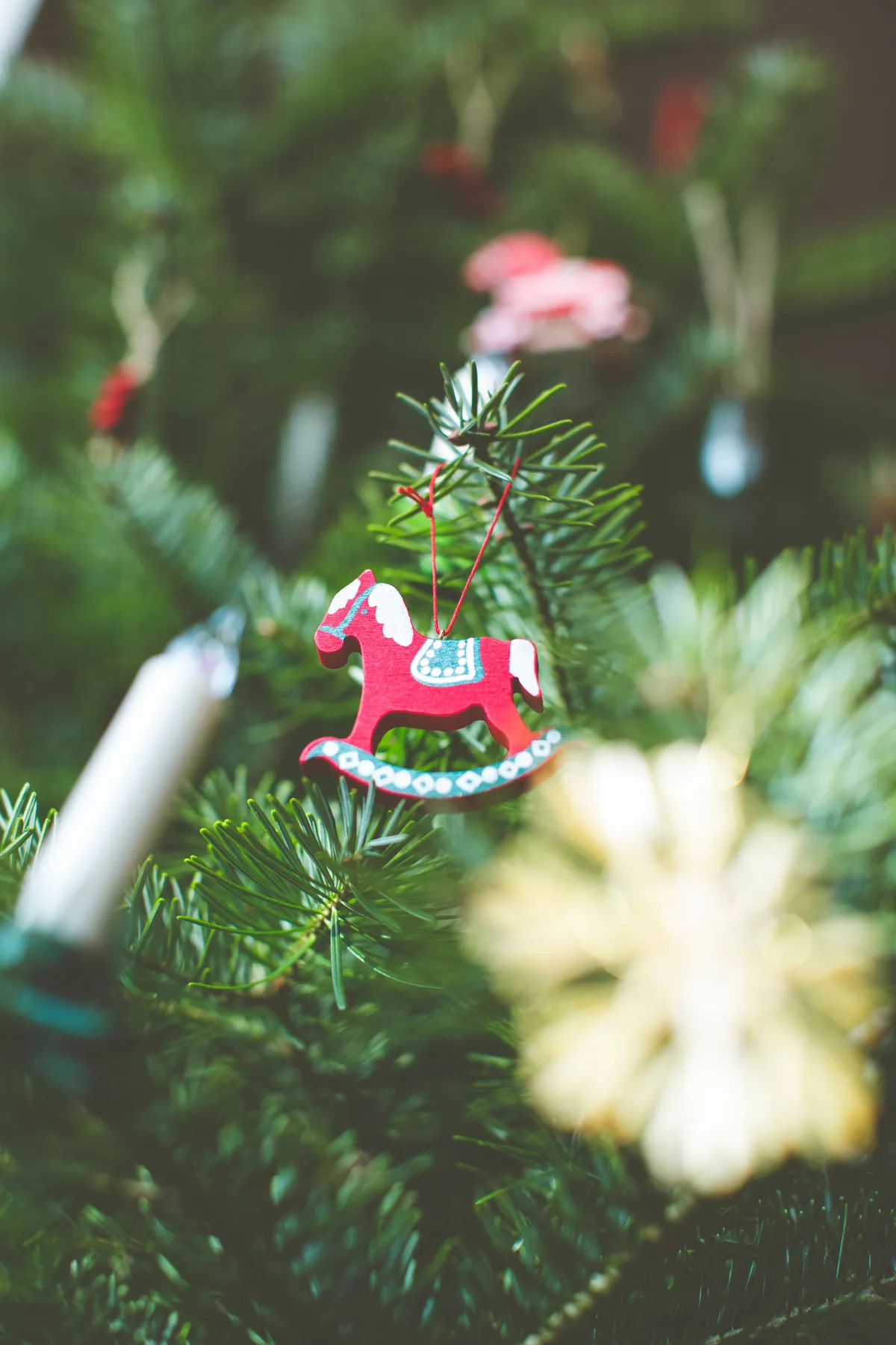 Close-up of a Christmas tree decorated with a colorful rocking horse ornament.