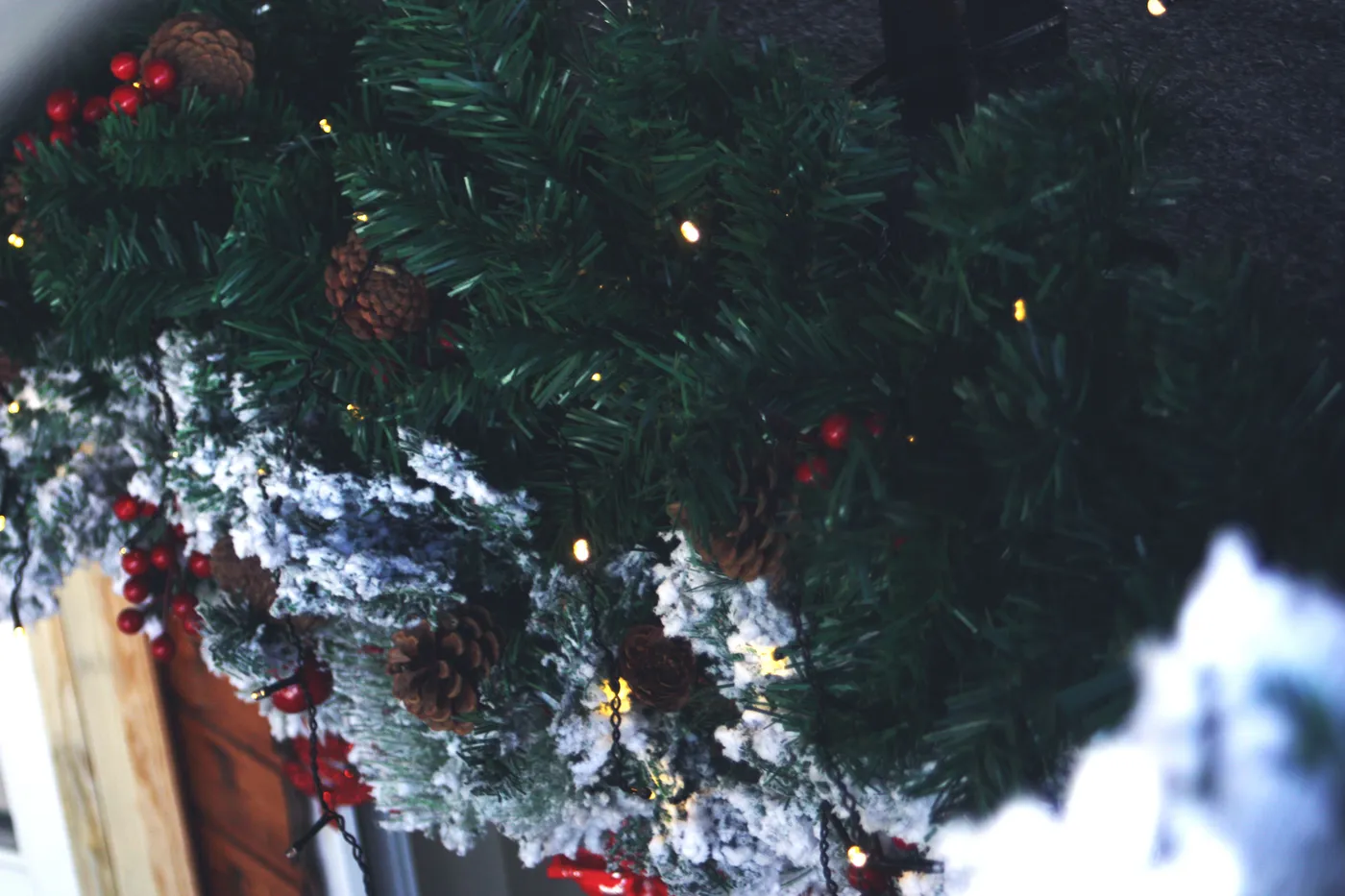 Close-up of a decorated Christmas garland with pinecones, berries, and lights, capturing the festive spirit.