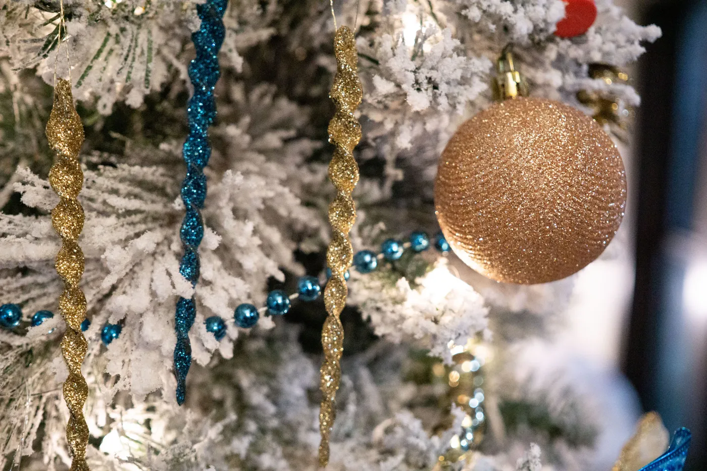 Close-up of a decorated Christmas tree with glittering ornaments and snow-dusted branches, capturing holiday spirit.