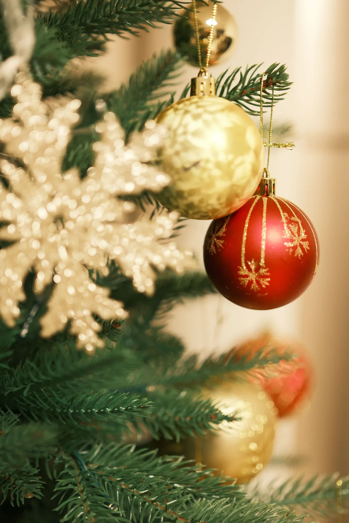 Close-up of a decorated Christmas tree with red and gold ornaments and a snowflake.