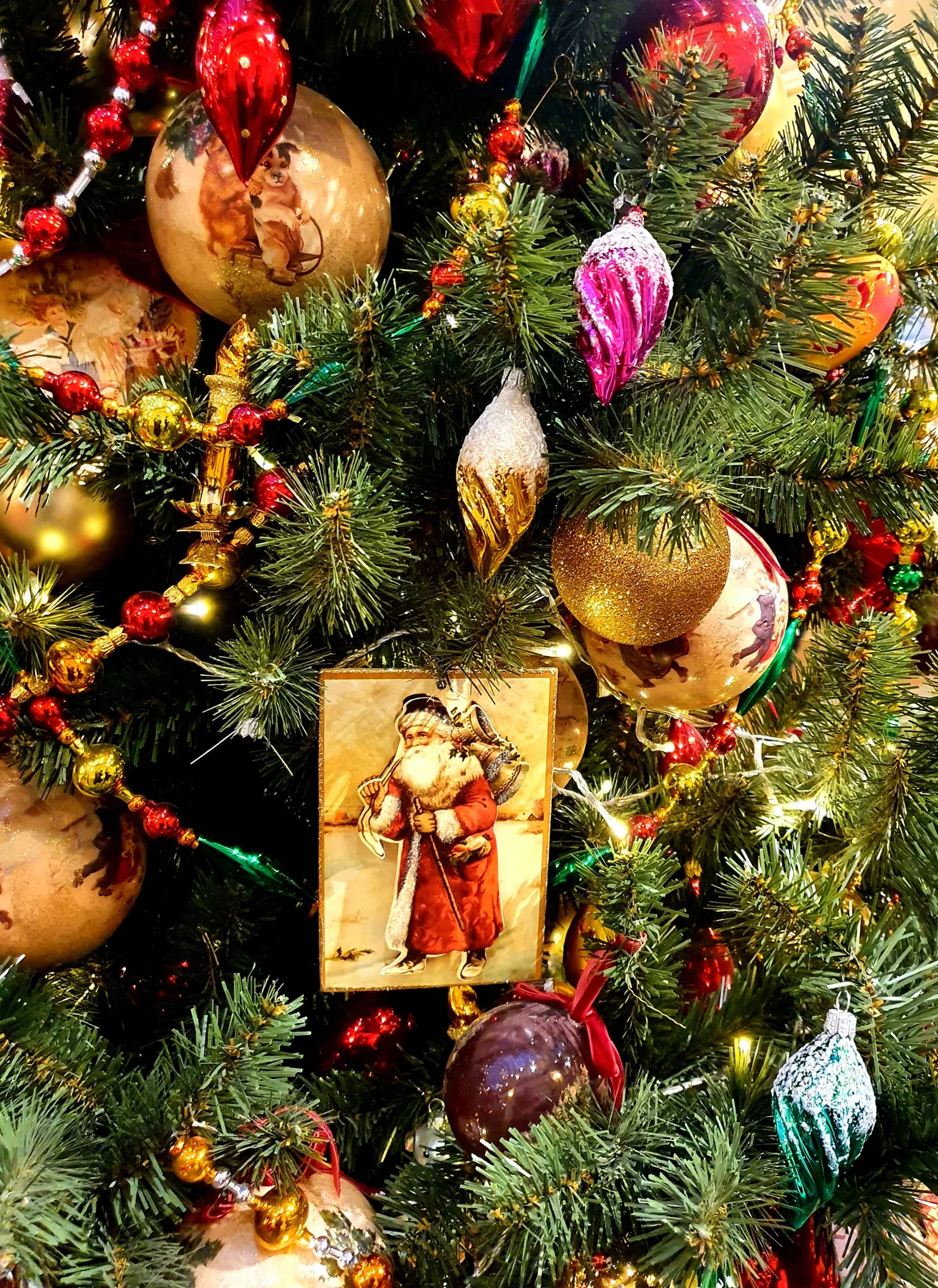 Close-up of a decorated Christmas tree with vintage ornaments and baubles in a festive setting.