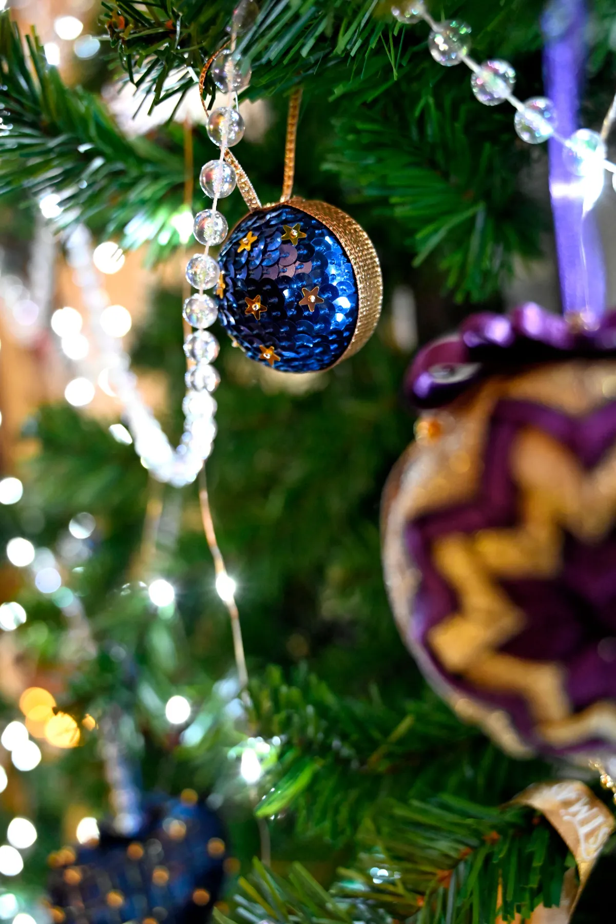 Close-up of colorful Christmas tree ornaments with lights for a festive holiday season.