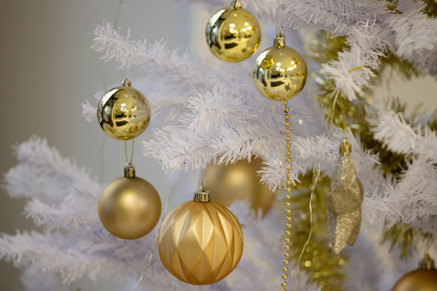 Close-up of gold baubles on a white Christmas tree, festive and elegant.