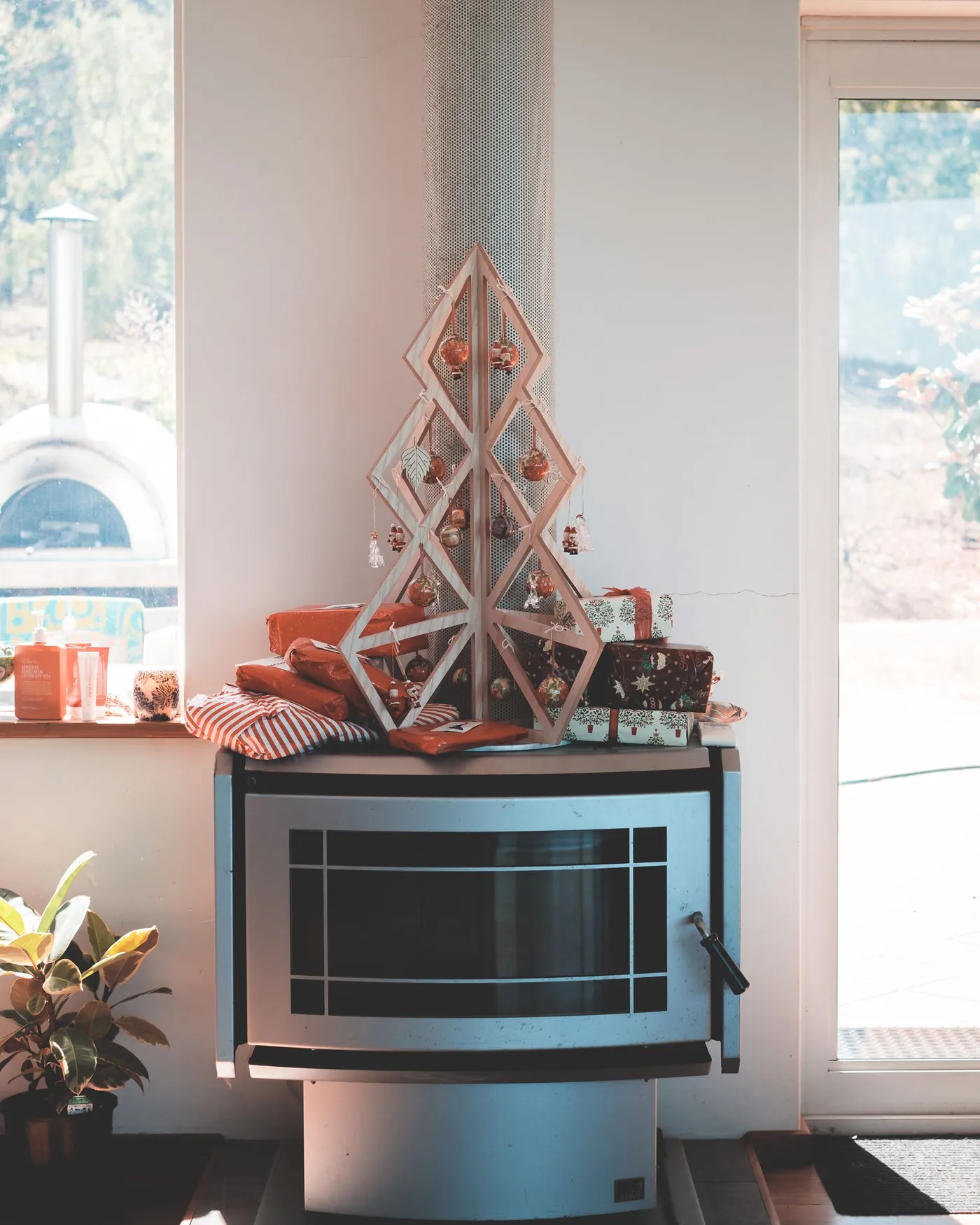 Contemporary fireplace with geometrical wooden Christmas tree decorated with tiny baubles in living room