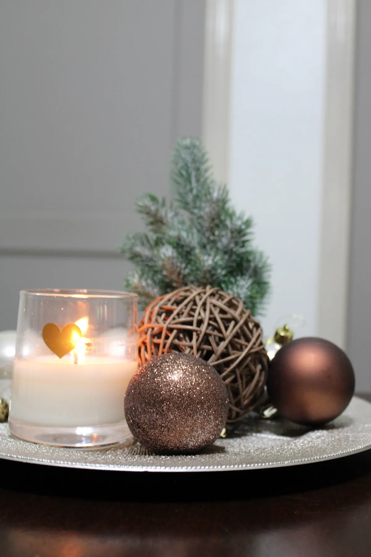 Cozy and elegant Christmas-themed candle arrangement with festive ornaments.