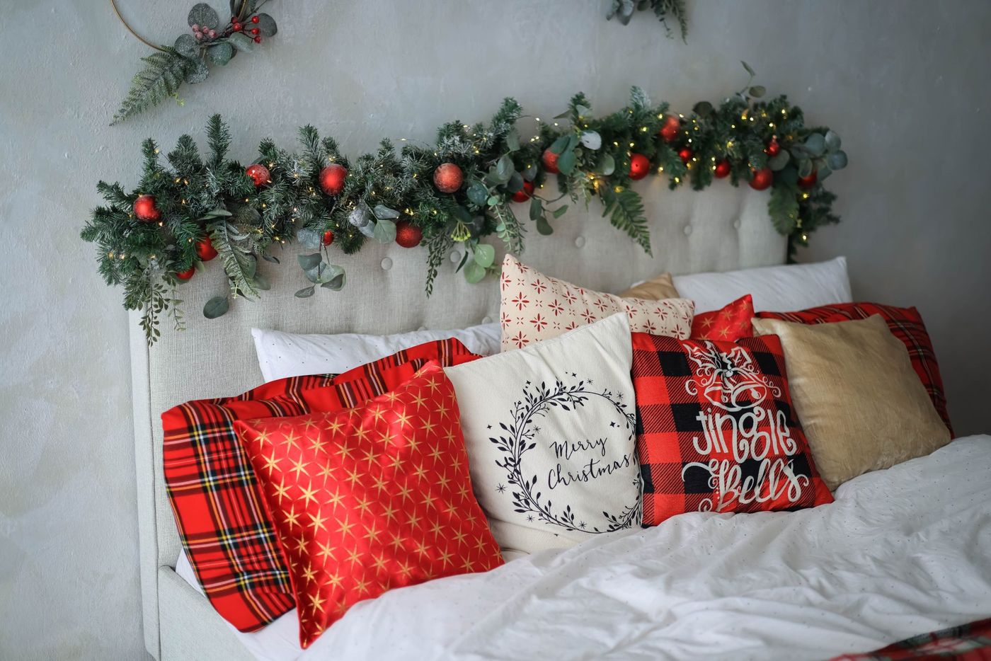 Cozy bedroom with Christmas decorations, pillows, and garland lights.