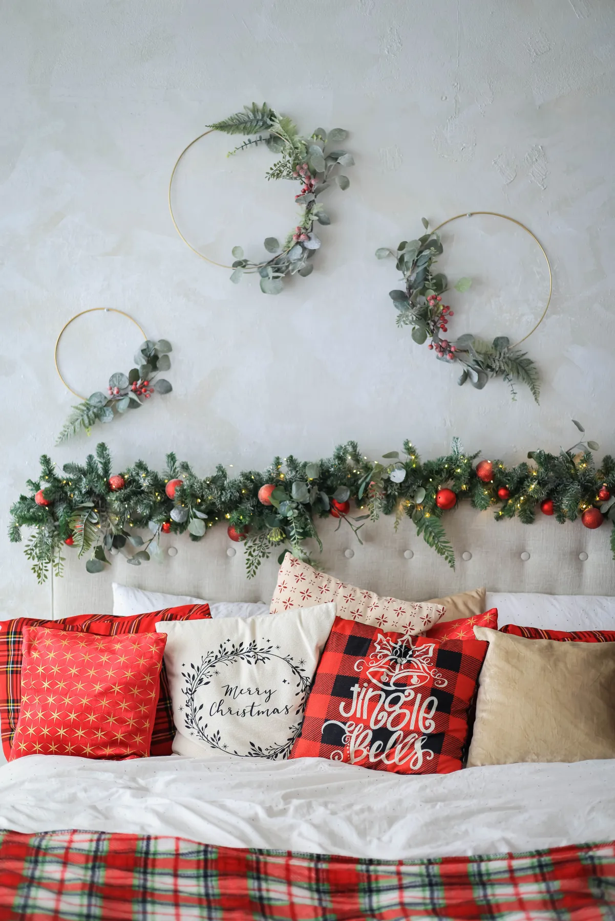 Cozy bedroom with Christmas garlands and decorative pillows, perfect for festive inspiration.