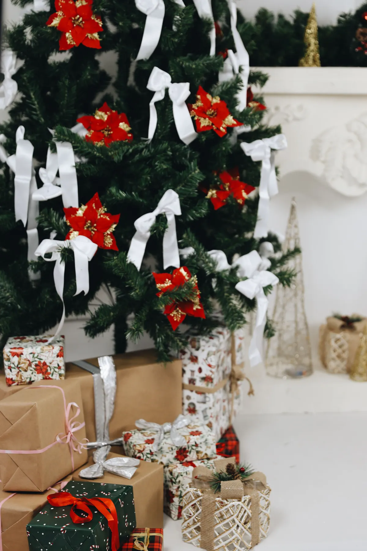 Decorated Christmas tree with red poinsettias and gifts underneath, capturing holiday spirit.