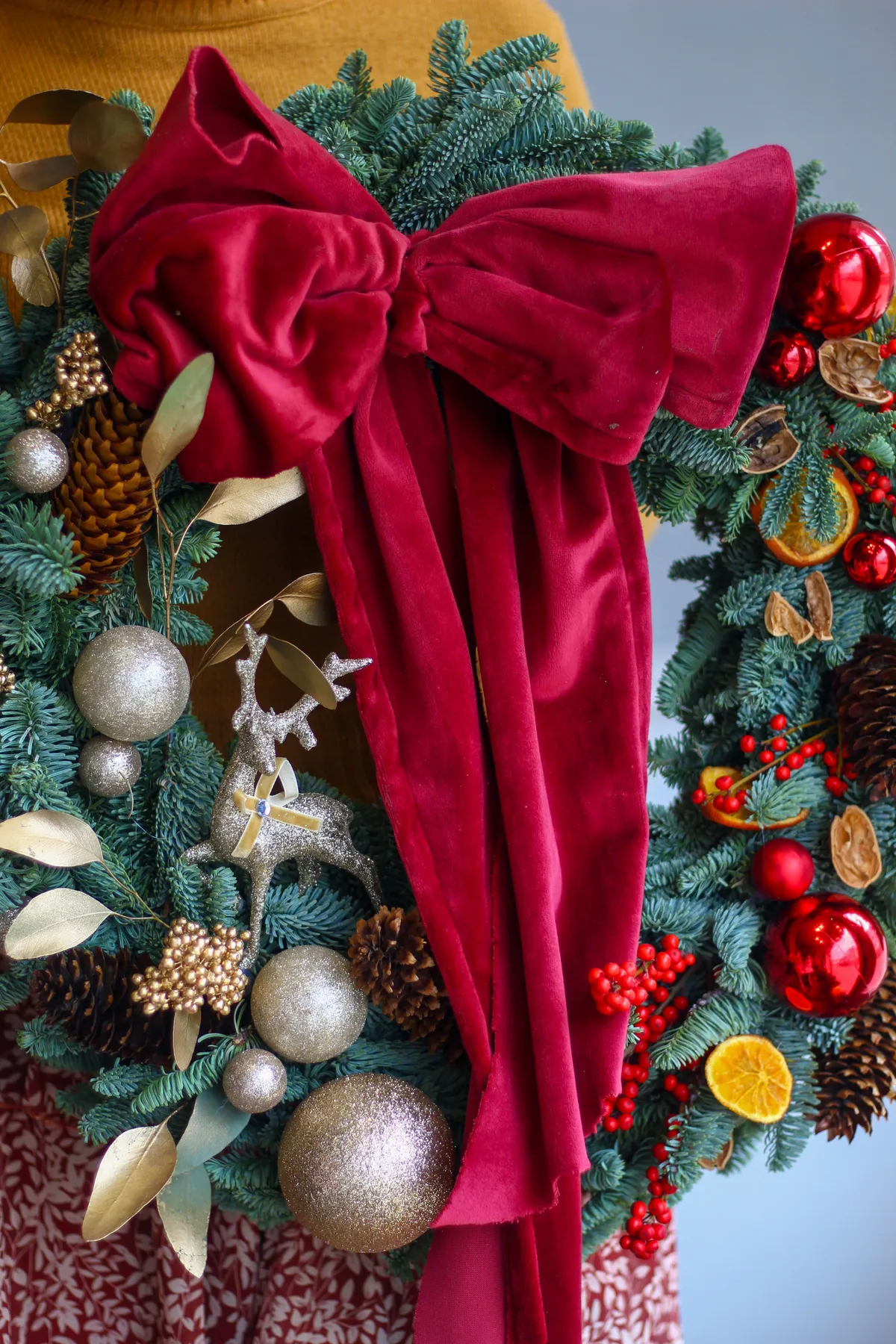 Detailed close-up of a decorative Christmas wreath featuring a large red velvet bow and festive ornaments.