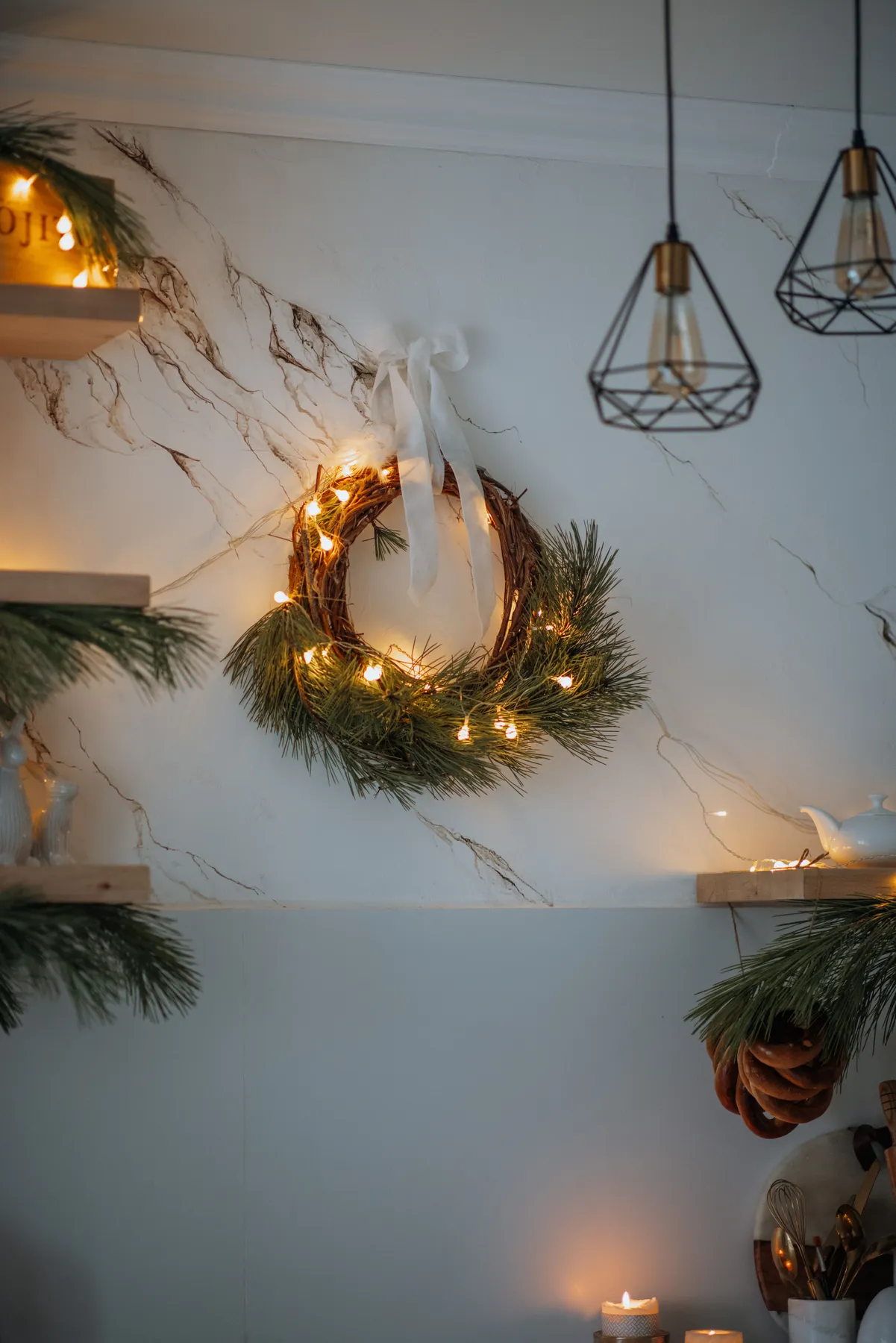 Elegant Christmas decoration in a stylish kitchen with a lit wreath and candles.