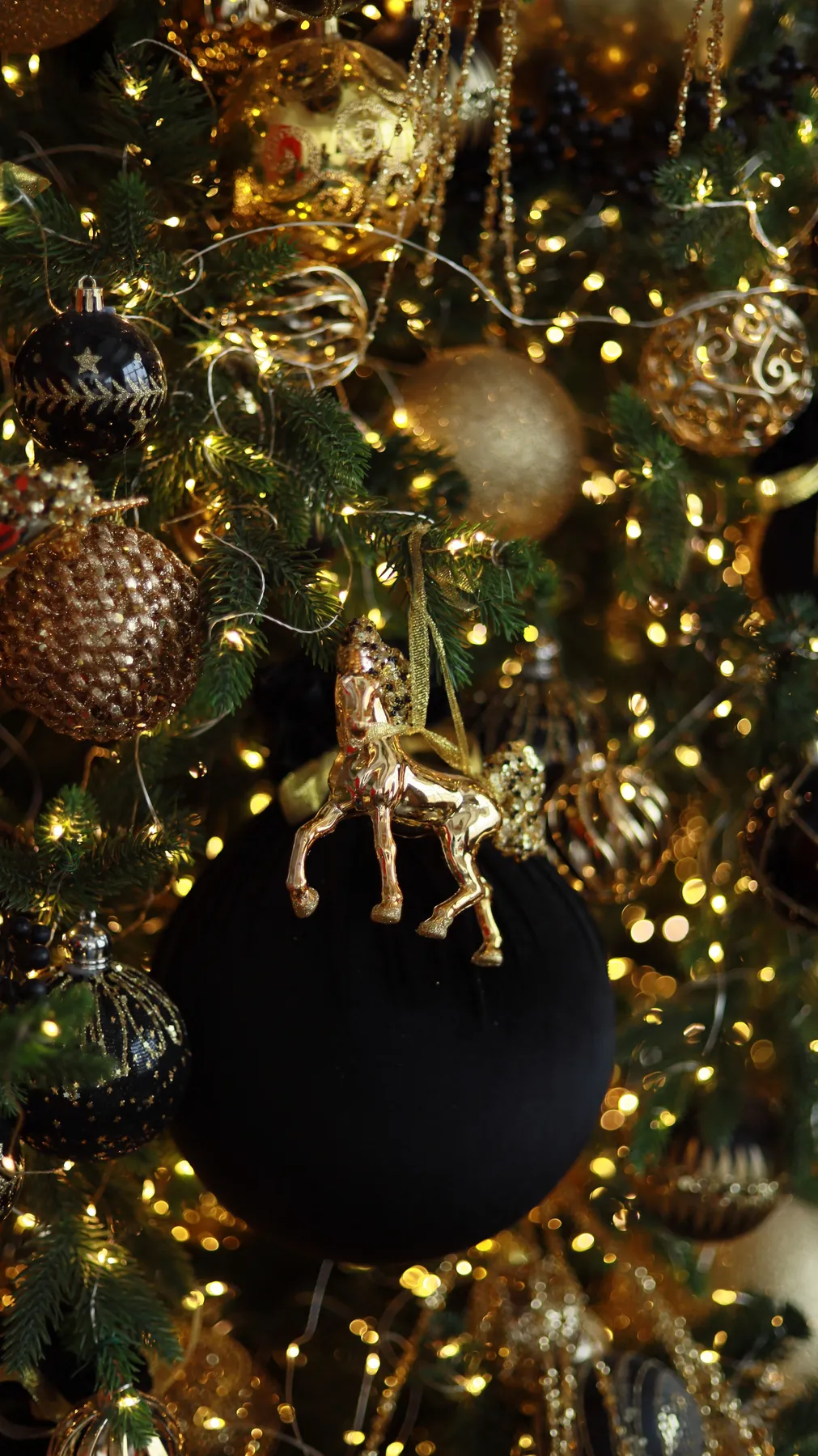 Elegant Christmas tree adorned with gold ornaments and lights, creating a festive atmosphere.