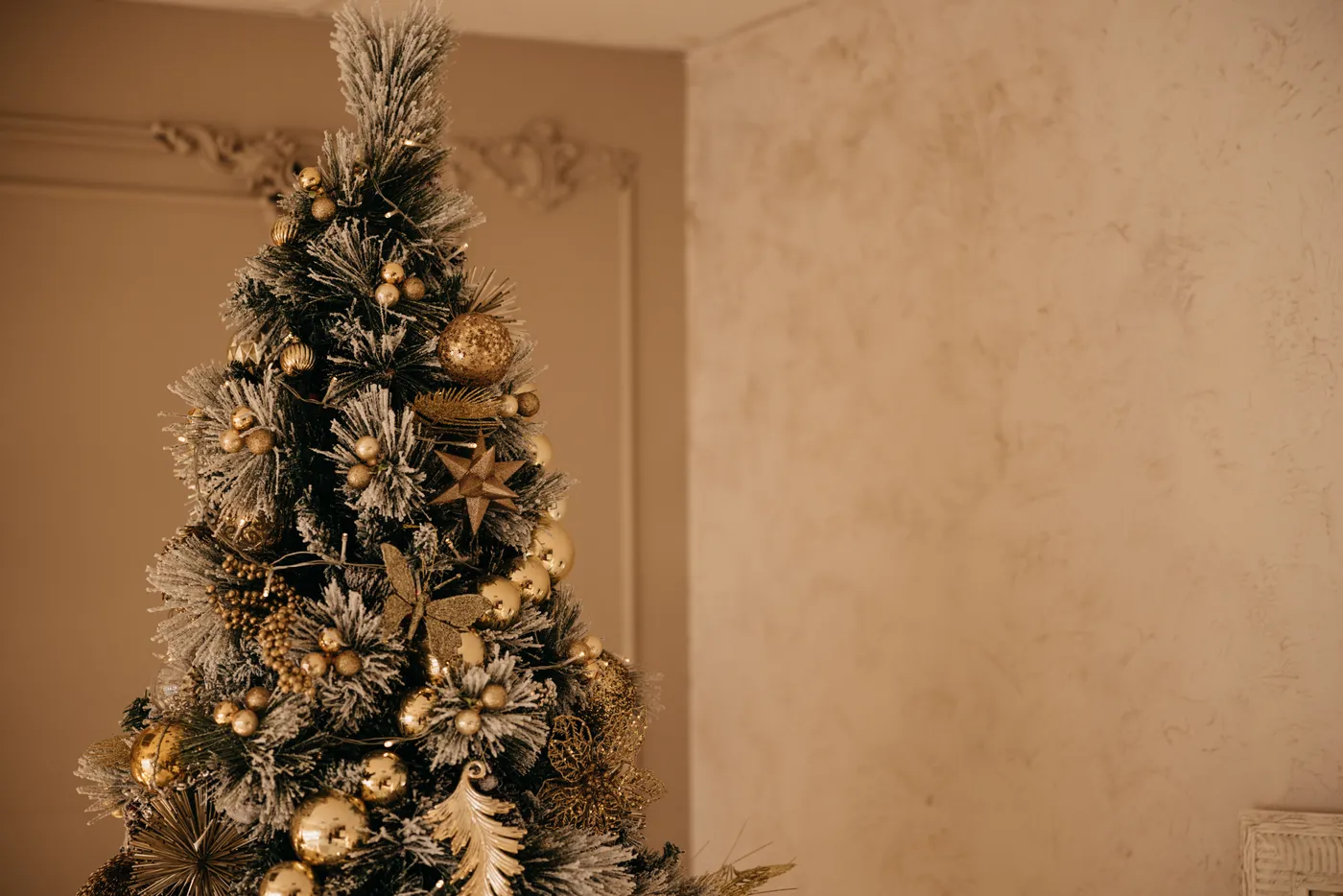 Elegant Christmas tree adorned with golden ornaments and festive decorations indoors.