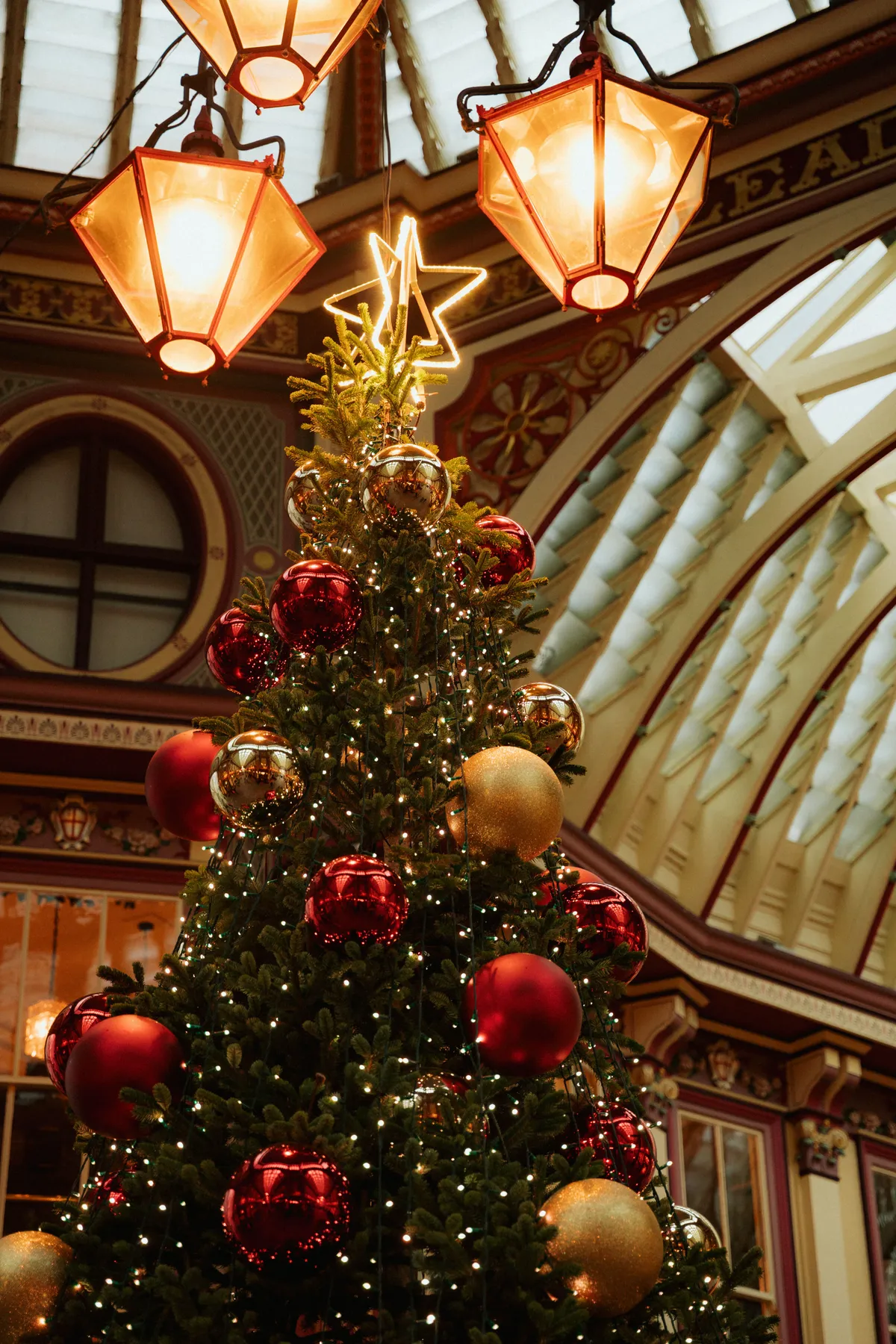 Elegant Christmas tree with ornaments inside a vintage-style shopping arcade.