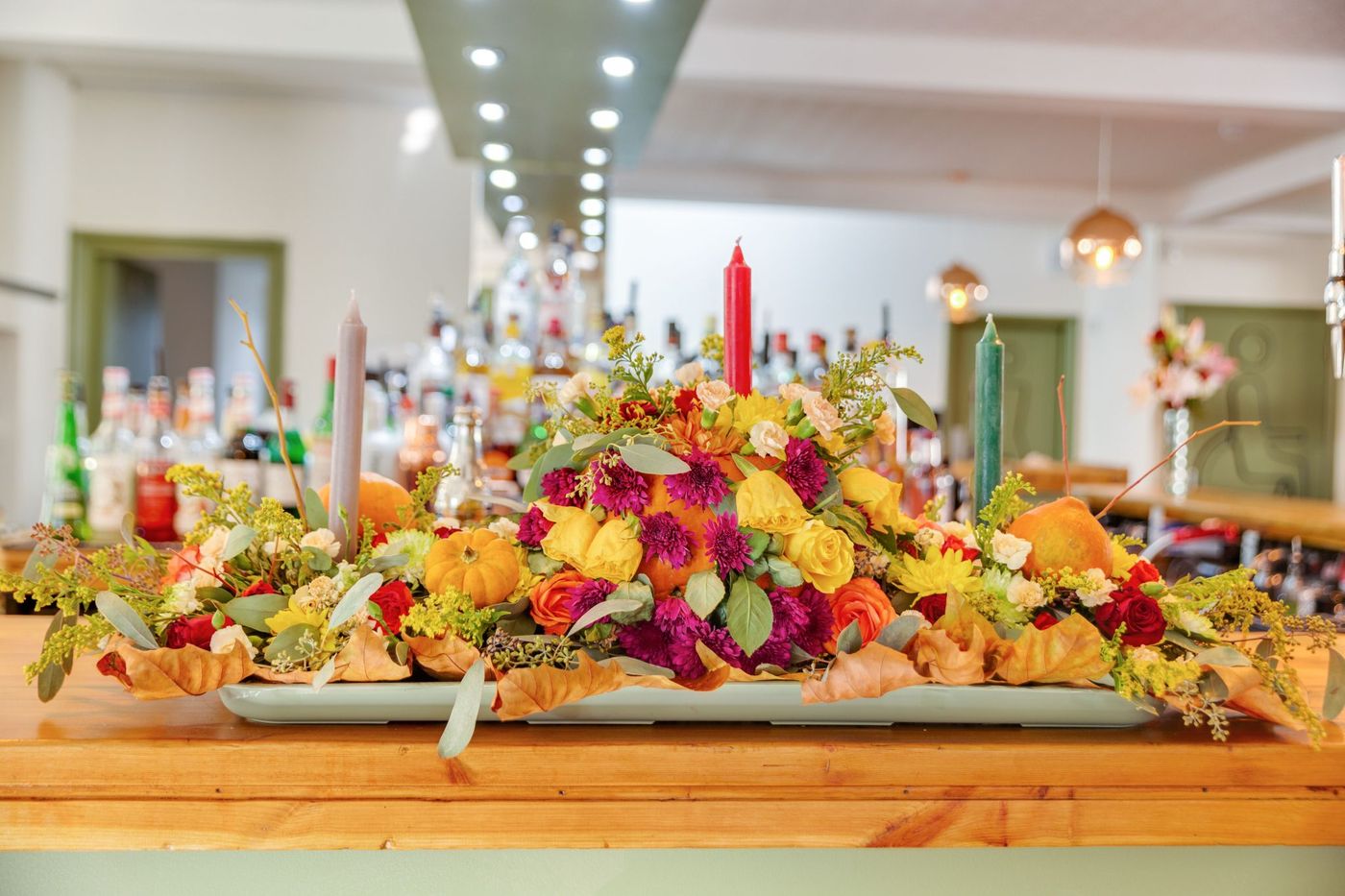 Elegant flower arrangement with vibrant autumn colors and candles, perfect for festive celebrations.