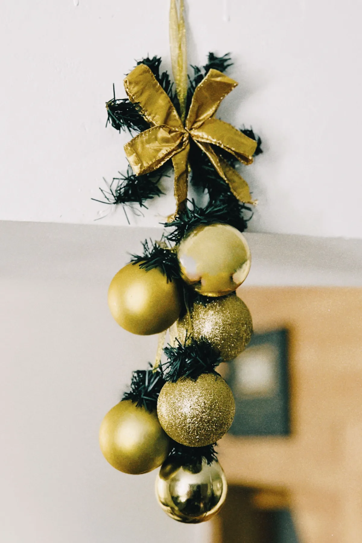 Elegant golden Christmas ornaments with ribbon and greenery for festive holiday décor.