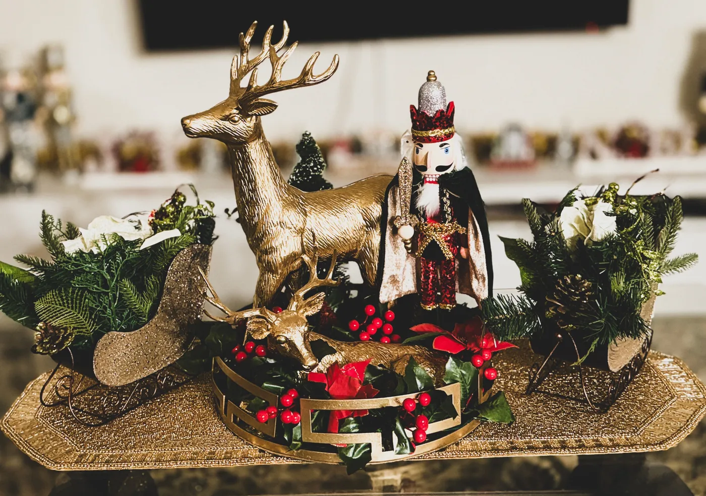 Elegant holiday centerpiece featuring a nutcracker, reindeer, and festive greenery on a gold tray.