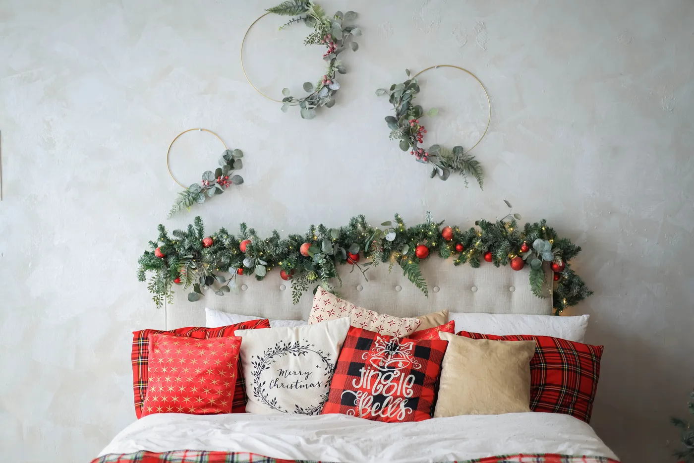 Festive Christmas bedroom with decorated headboard and cozy, themed pillows creating a warm holiday ambiance.