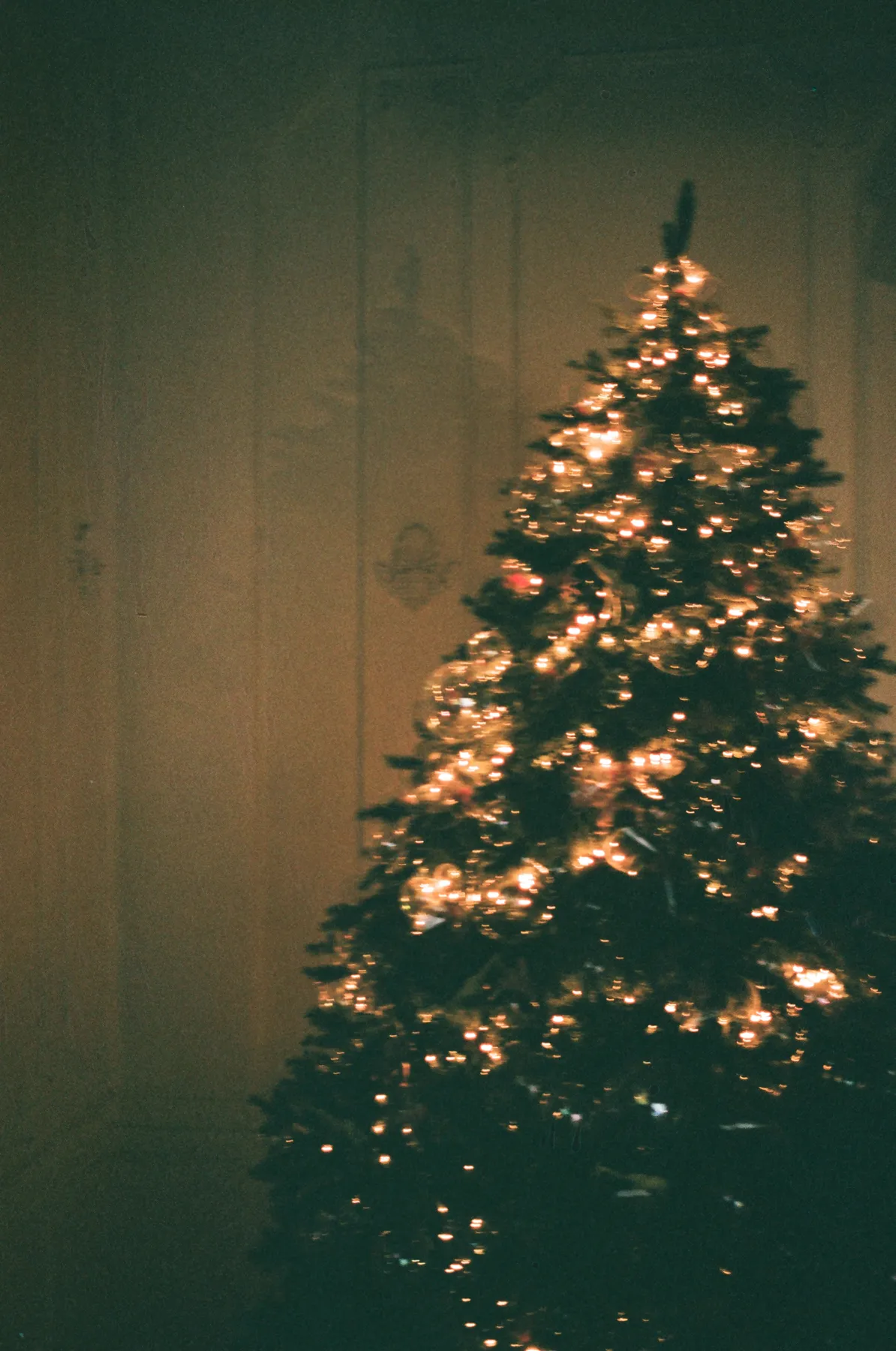 Festive Christmas tree adorned with glowing lights captured through analog photography.