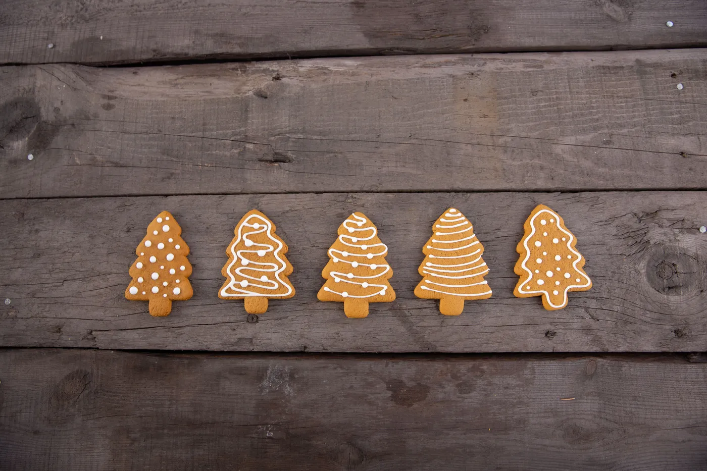 Festive gingerbread cookies shaped like Christmas trees on rustic wooden background. Perfect holiday treat.