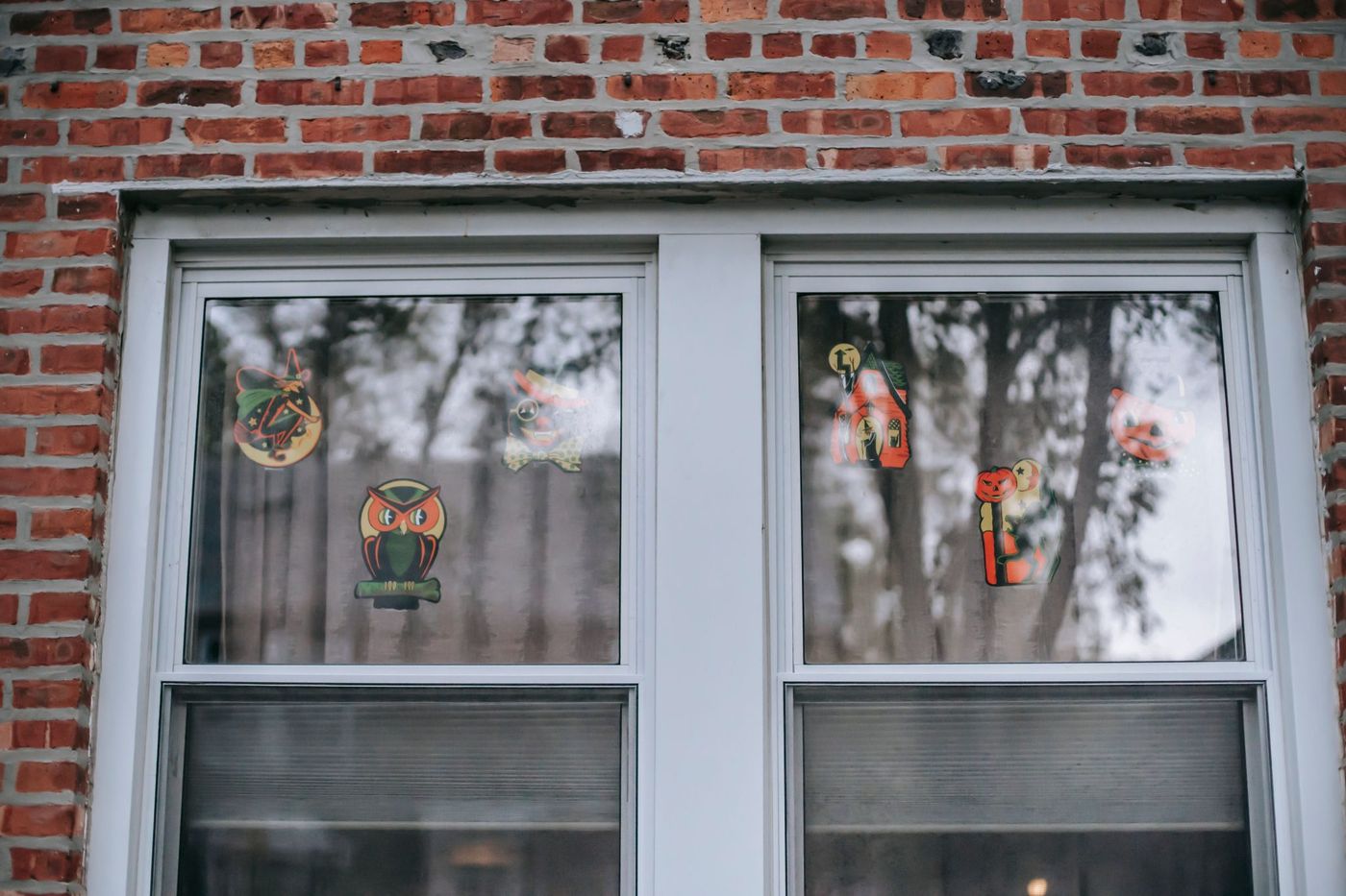 Fragment of window with various decorative elements of Halloween stickers on glass of residential building with brick wall during holiday celebration
