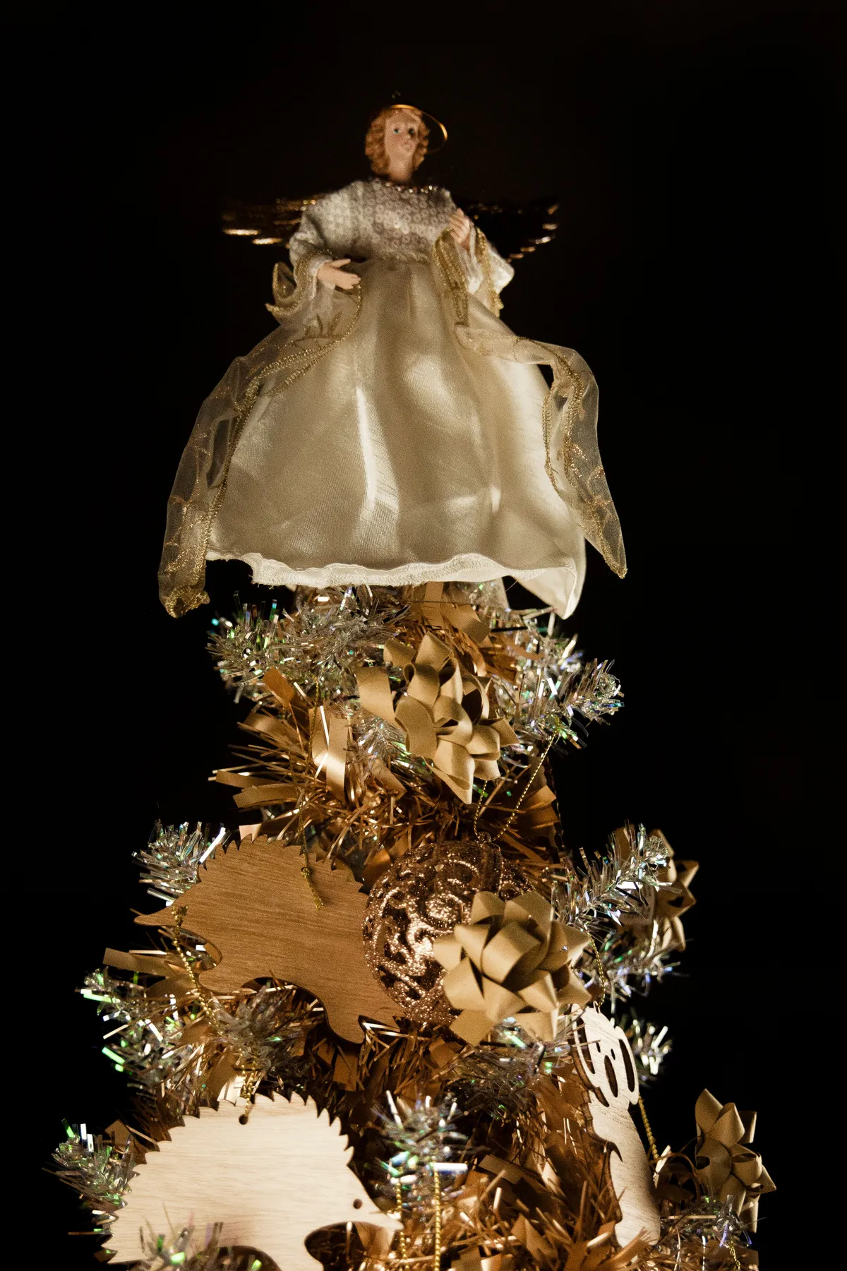 Gold and white angel figurine tops an elegantly decorated Christmas tree.